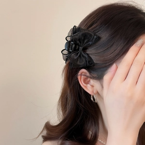 Detailed close-up of elegant black tulle bow hair claw clip worn on model hair