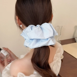 Chouchou avec broderie papillon bleu présenté dans un style de queue de cheval basse élégant