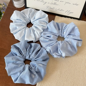 Lot de trois chouchous bleus avec imprimés papillon sur une table en bois rustique