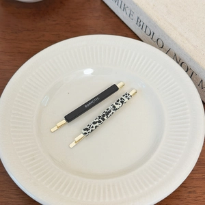 Minimalist acetate hair clips in solid black and leopard print with gold metal base