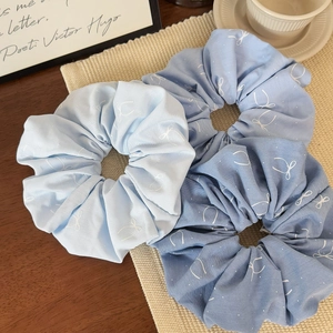 Lot de trois chouchous bleus à motifs papillons sur un tapis beige tressé