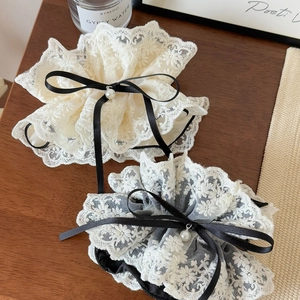 Détail de chouchous en dentelle multicouche avec nœuds noirs et pendentifs en perles