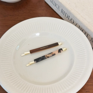 Set of two vintage acetate hair clips in tortoise shell and amber patterns on ceramic plate