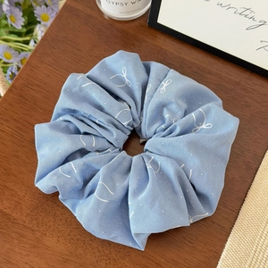 Détail de chouchou bleu clair à imprimé papillon sur un fond de table en bois