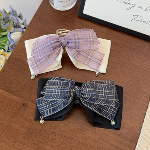 Elegant bow hair clips with plaid ribbons and teardrop pendants on a wooden background