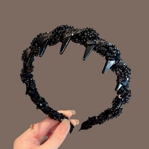 Close-up of black beaded headband with sequin texture and spiked design detail