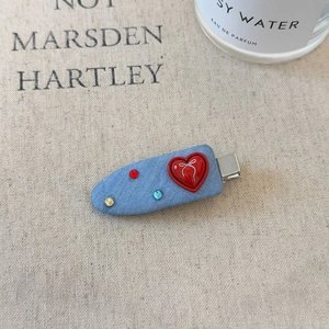 Detail of denim blue hair clip featuring a red resin heart and colorful rhinestones
