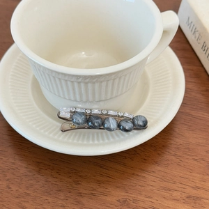 Elegante fermaglio argento con pietre marmorizzate grigie e strass vicino a tazza
