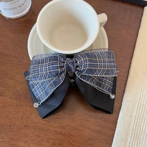 Detail of a double-layered plaid bow hair clip with crystal pendants and satin base