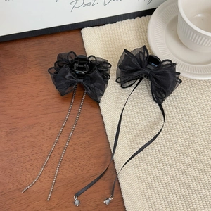 Detail of elegant black mesh bow hair clips with crystal fringes and beads on a wooden desk