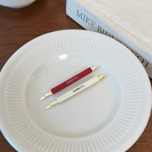 Detail of red and cream vintage acetate hair clips on a white ceramic plate decoration