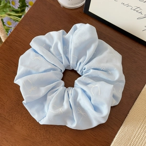 Détail du chouchou bleu clair à imprimé papillon blanc sur surface en bois