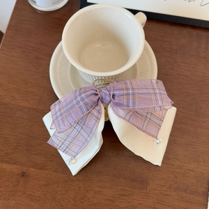Detail of a purple plaid and beige ribbon hair claw clip with crystal bead accents