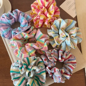 Detailed macro view of seven colorful striped scrunchies with ribbed fabric texture