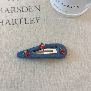 Detailed view of denim hair clip featuring red rhinestone cherry and green enamel leaf