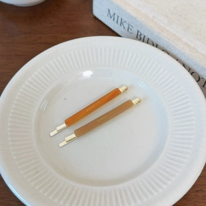 Macro detail of amber and light brown acetate hair pins set in a white decorative tray