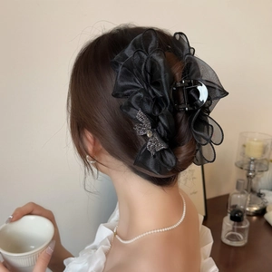Détail d'une grande pince à cheveux avec nœud en maille noire et strass sur modèle