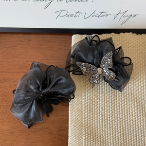 Détail de la pince à cheveux en tulle noir avec nœud papillon et papillon en strass brillant