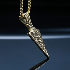 Detailed macro view of gold-colored arrow pendant with textured surface on box chain