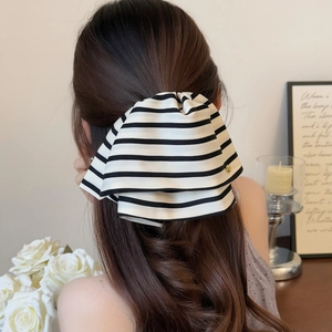 Elegant black and white striped bow hair clip with gold metal emblem detail for women