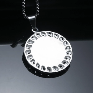 Vue détaillée du revers du pendentif rond argenté avec découpes et chaîne maille miroir