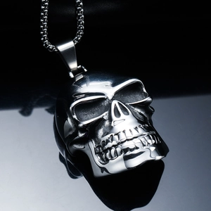 Détail macro du pendentif crâne en acier poli avec des reflets noirs de style punk