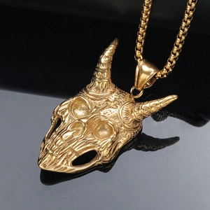 Ciondolo teschio punk con corna di ariete oro e catena box su fondo riflettente