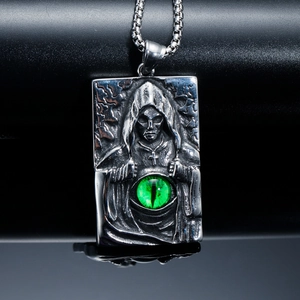 Gros plan d'un pendentif gothique faucheuse en acier vintage avec gemme œil de chat vert