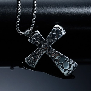 Close-up of gothic cross pendant with stone texture on stainless steel chain