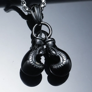 Pendentif gants de boxe noirs hip-hop avec chaîne à billes sur surface réfléchissante