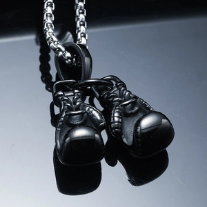 Vue macro du pendentif gants de boxe plaqué noir sur une chaîne à mailles carrées argent