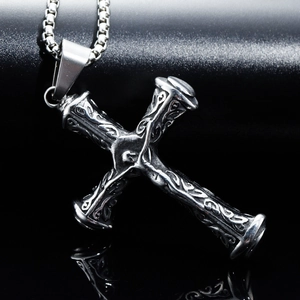 Macro detail of vintage stainless steel cross pendant with tribal vine engravings
