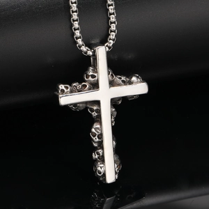 Macro shot of polished stainless steel cross pendant featuring gothic skull details and box chain