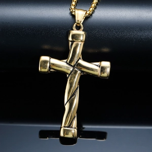 Gros plan du pendentif croix en acier doré avec texture torsadée et chaîne vénitienne