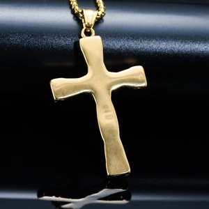 Vue macro du collier croix dorée avec texture ondulée et finition métallique polie