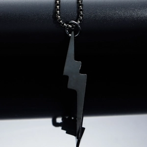 Collier avec pendentif éclair noir minimaliste en acier inoxydable sur surface réfléchie