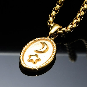 Golden oval pendant necklace with embossed moon and star patterns on a box chain