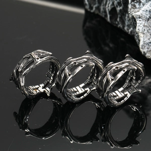 Gothic thorn crown rings in vintage black stainless steel on a dark rock background