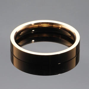 Polished gold stainless steel minimalist ring with a mirror reflection on grey surface