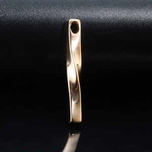 Detail shot of a twisted spiral rectangular bar pendant in polished gold stainless steel