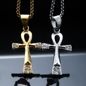 Polished gold and silver Ankh cross pendants with zircon inlay on dark reflective background