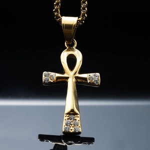 Macro shot of gold Ankh cross pendant with rhinestone accents on a beaded chain