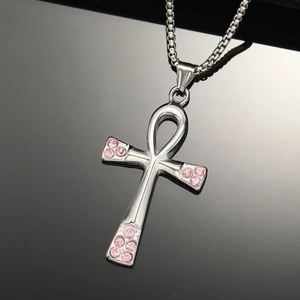 Macro shot of silver Ankh cross pendant with pink rhinestones on a black surface