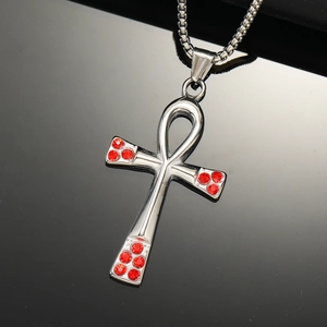 Macro detail of polished Ankh cross pendant with red rhinestones on a black surface