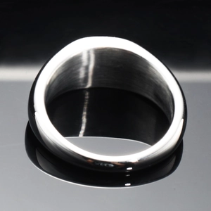 Bague large en acier inoxydable poli argenté sur une surface réfléchissante noire