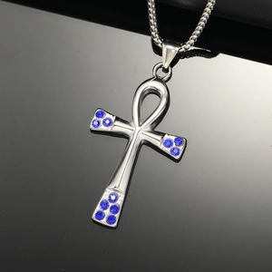 Detailed macro view of silver Ankh cross pendant with blue rhinestones on box chain