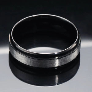 Minimalist brushed stainless steel ring with black step edges on a reflective surface