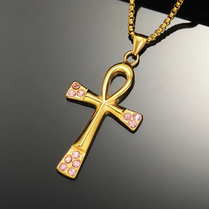 Close-up of golden Egyptian Ankh cross pendant with sparkling pink rhinestones