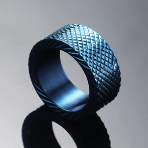 Macro shot of dark blue stainless steel ring with diamond-knurled texture and beveled edges