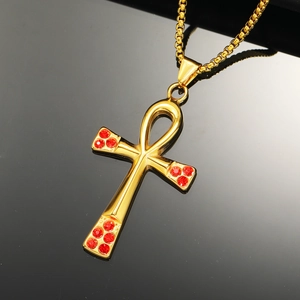 Macro view of gold Ankh cross pendant with red rhinestone inlay and box chain